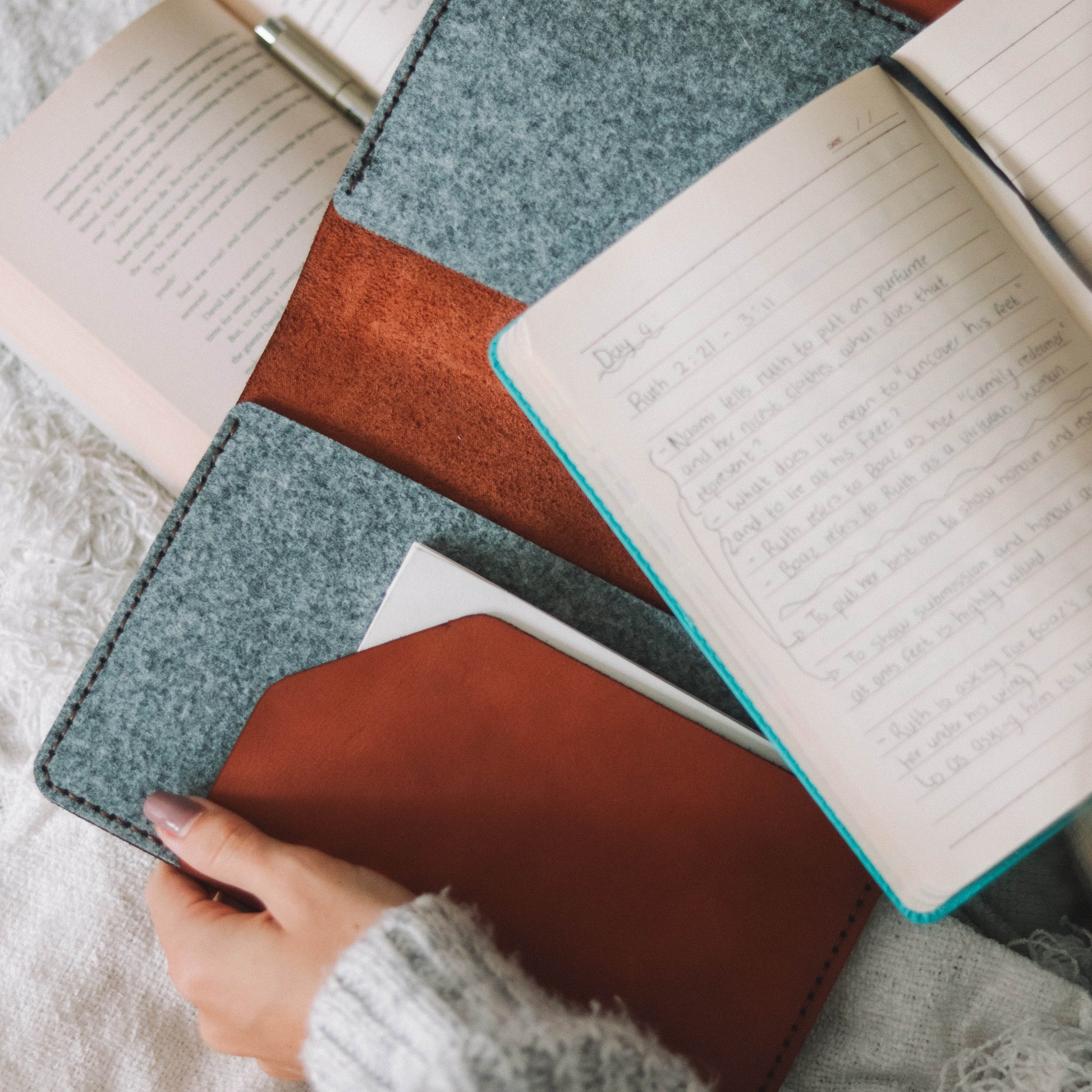 Open notebooks with colorful covers on a textured surface, with a hand holding one of them.